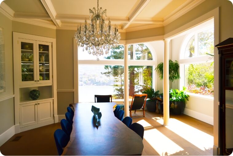 A beautifully designed dining room featuring a chandelier and large windows overlooking a scenic view.