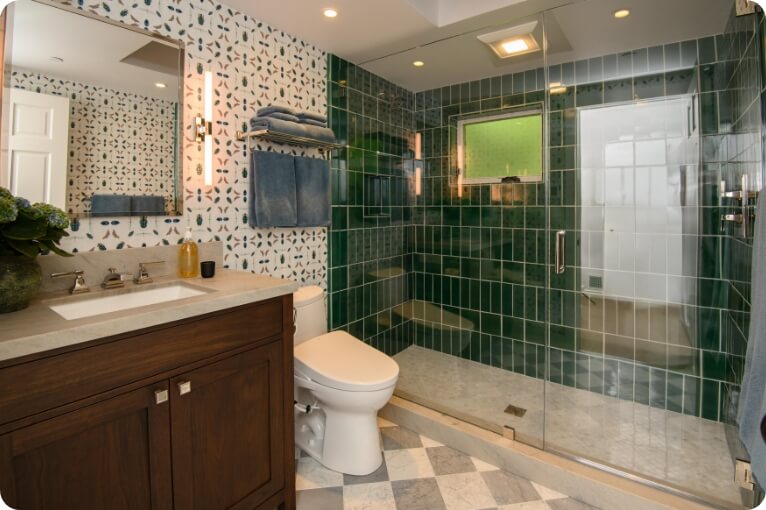 A stylish modern bathroom featuring green tile and a glass shower.